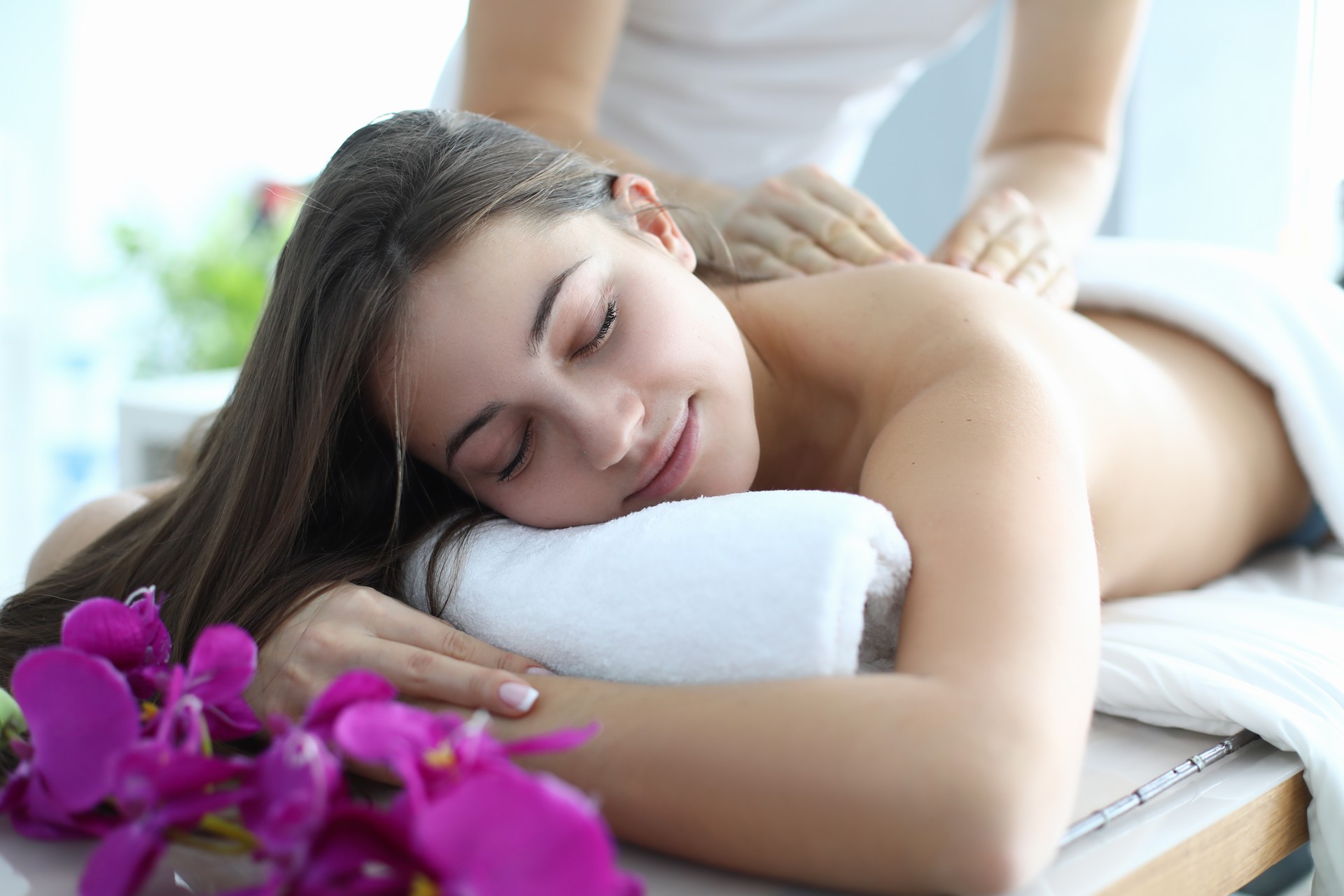 Man do massage for beautiful woman, who lay on her stomach on massage table.