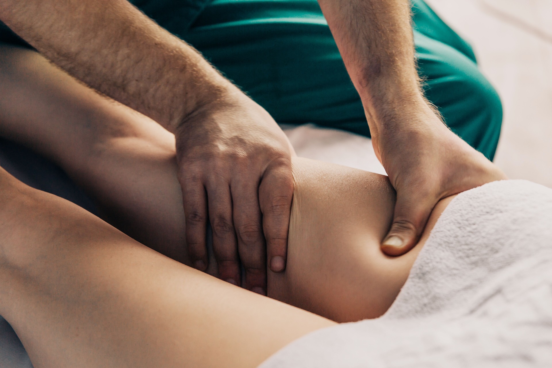 Lymphatic drainage massage of the hips. A male massage therapist gives a massage to a young woman